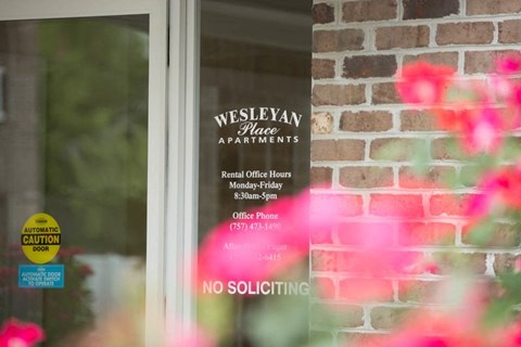 A window with a sign that says Wesleyan Place Apartments.