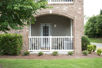 A white house with a brick archway and a white porch.