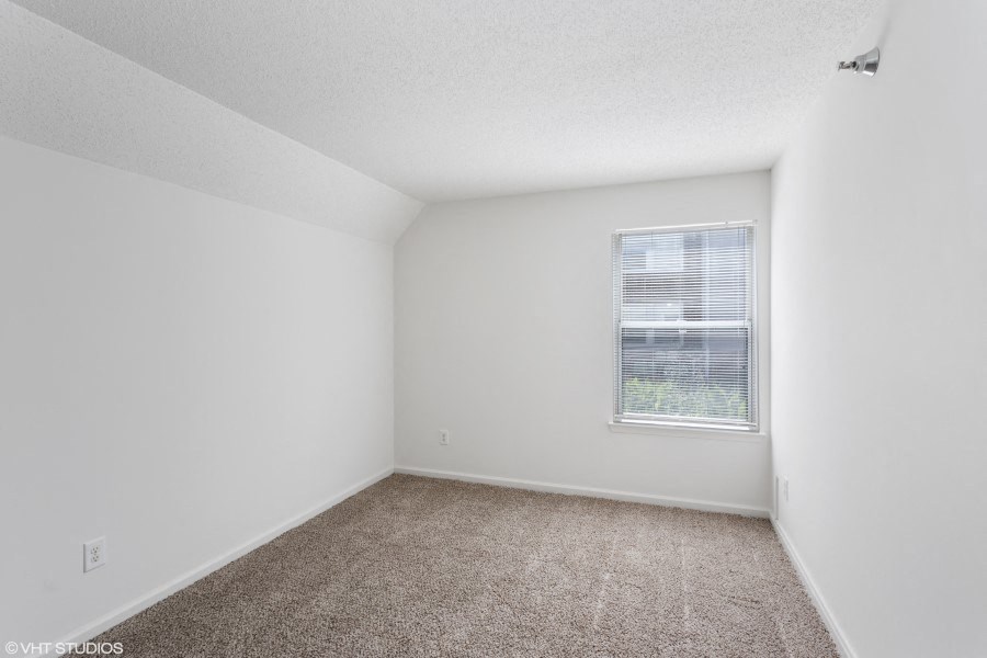 A room with a window and carpeted floor.