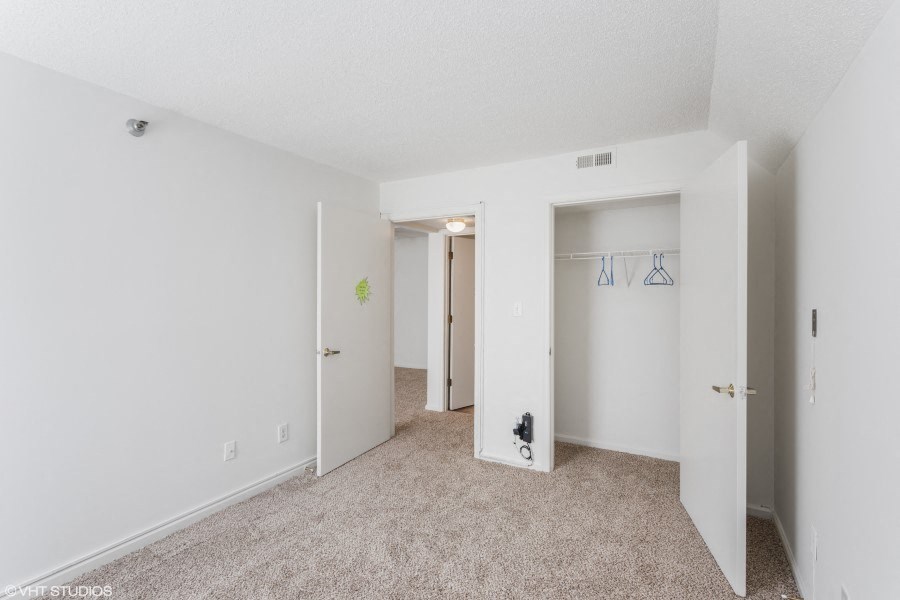 A white room with a carpeted floor and two open doors.
