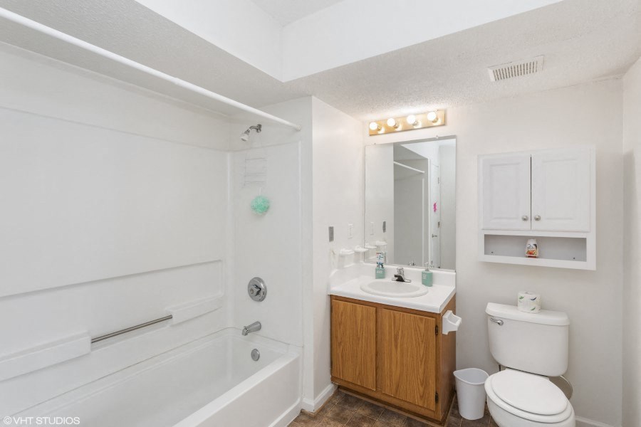A white bathroom with a wooden cabinet and a white toilet.