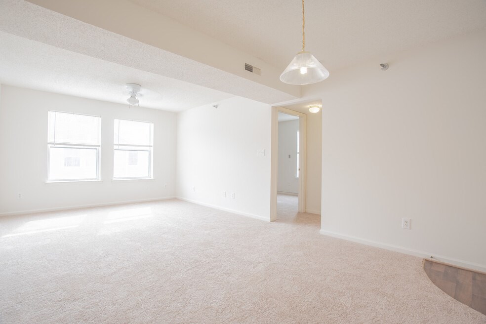 A large, empty room with a carpeted floor and a door leading to another room.