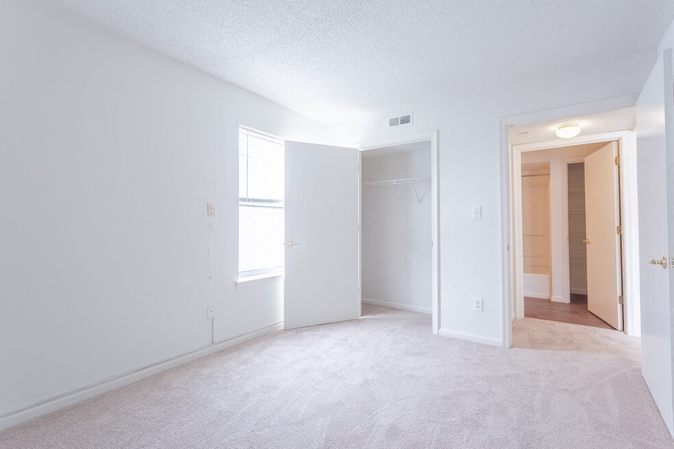 A white room with a carpeted floor and a door on the right side.