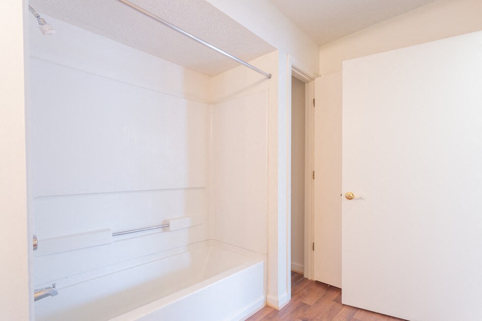 A white bathroom with a tub and a door.