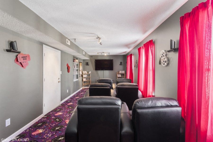 A room with black leather chairs and red curtains.