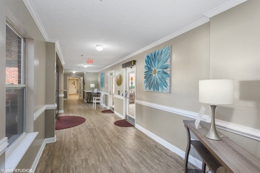A hallway with a red carpet and a white lamp.