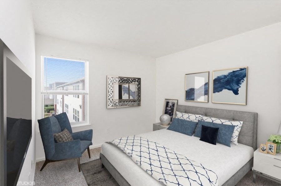 A bedroom with a large bed and a blue chair.