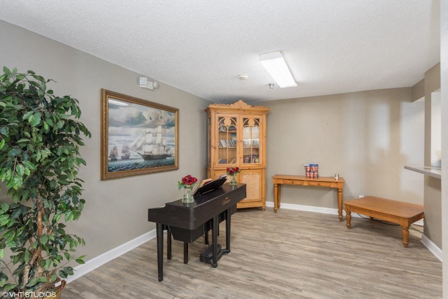A room with a piano, a bench, and a cabinet with glass doors.