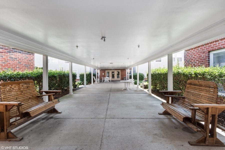 A long covered walkway with benches on either side.
