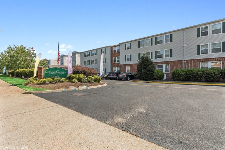 A parking lot in front of a building with a sign that reads "The Woodlands".