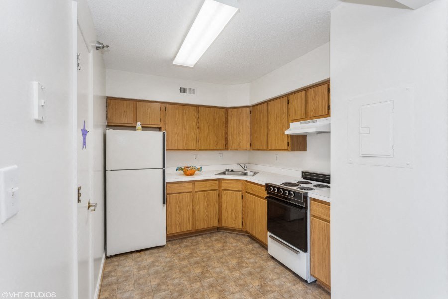 A kitchen with wooden cabinets and a white refrigerator.