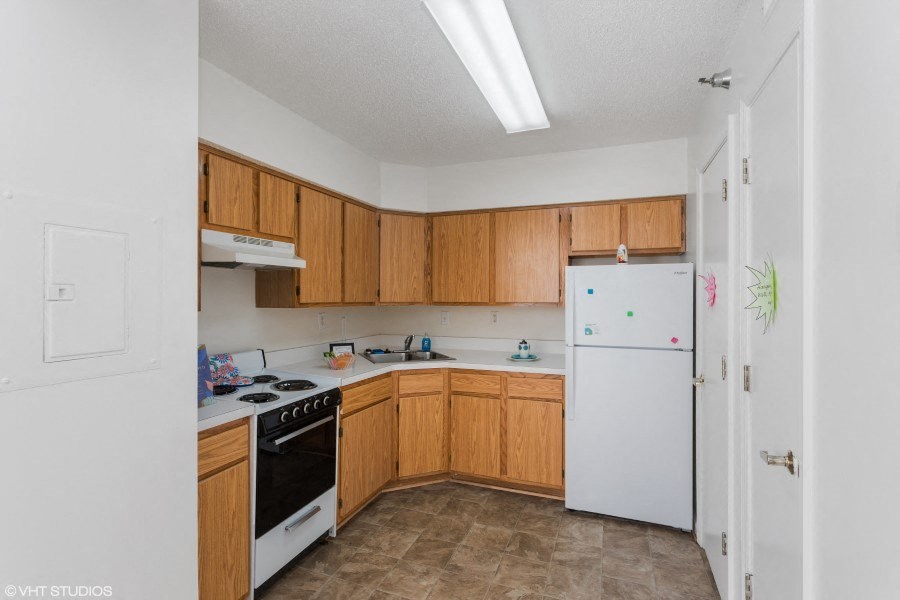 A kitchen with wooden cabinets and a white refrigerator.