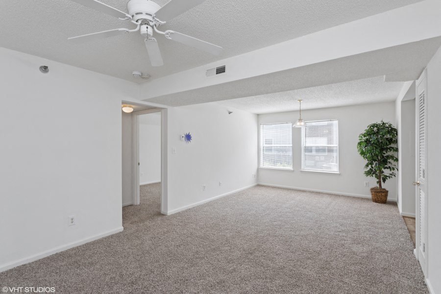A room with a ceiling fan and a carpeted floor.