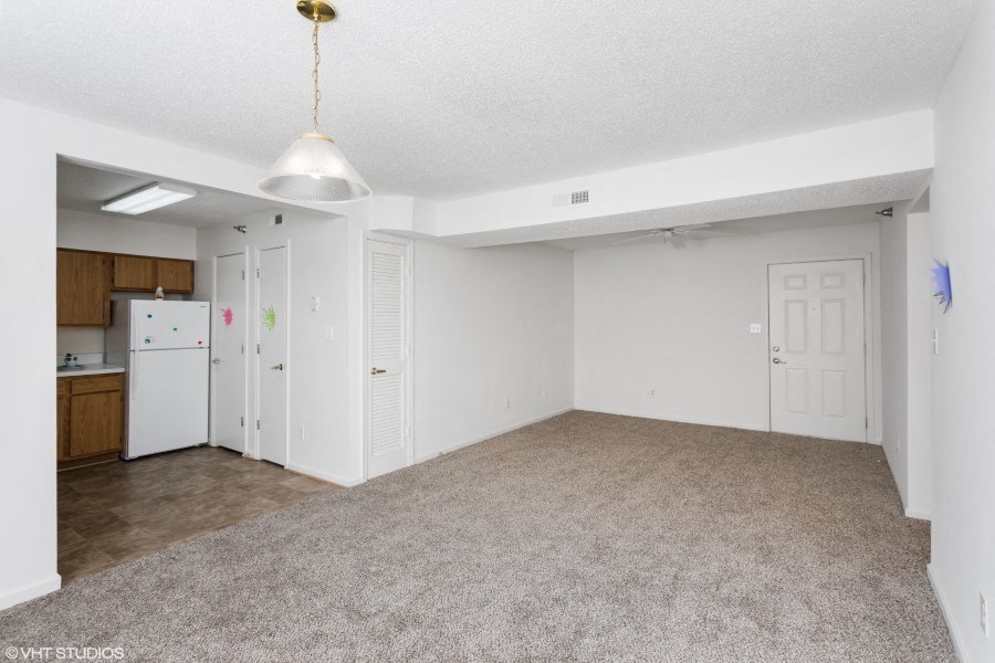 A spacious room with a carpeted floor and a ceiling light.