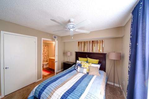 A bedroom with a bed, a ceiling fan, and a bookshelf.