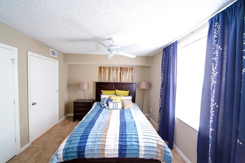 A bedroom with a bed, nightstand, and window with curtains.
