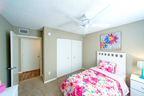 A bedroom with a bed, dresser, and a ceiling fan.