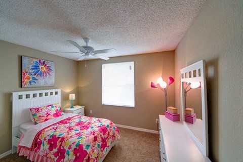 A bedroom with a bed, nightstand, and a painting on the wall.