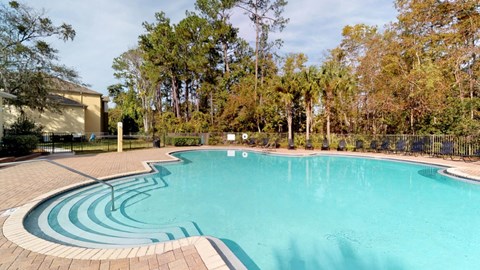 A large outdoor swimming pool surrounded by trees.
