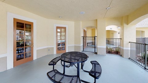 A patio with a table and chairs is surrounded by a black railing.