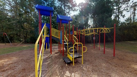 A playground with a yellow slide and blue and yellow swings.