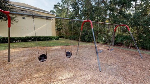 A playground with two swings and a red canopy.
