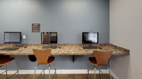 A room with a desk and chairs with a computer on it.