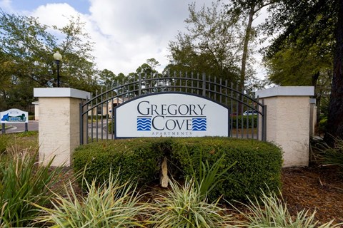 A sign that says Gregory Cove Apartments is displayed on a gate.