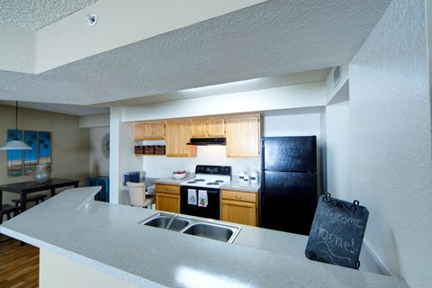 A kitchen with a black refrigerator and a chalkboard sign on the counter.