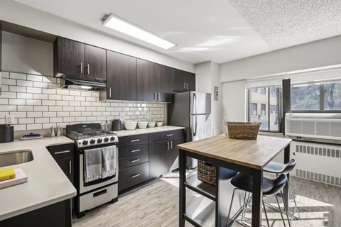 A kitchen with black cabinets and a stove top oven.