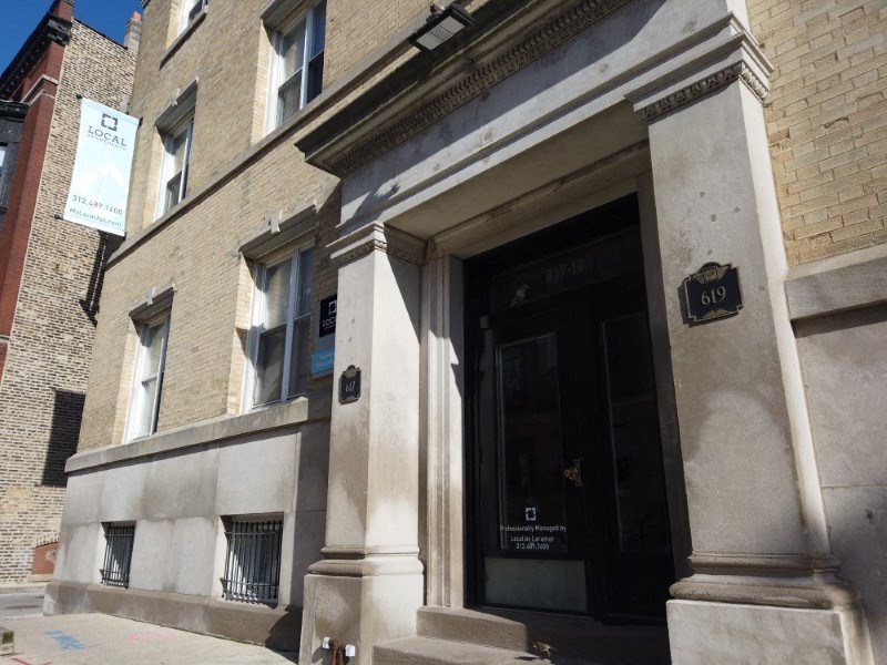 The image shows a building with a black door and a sign that reads 