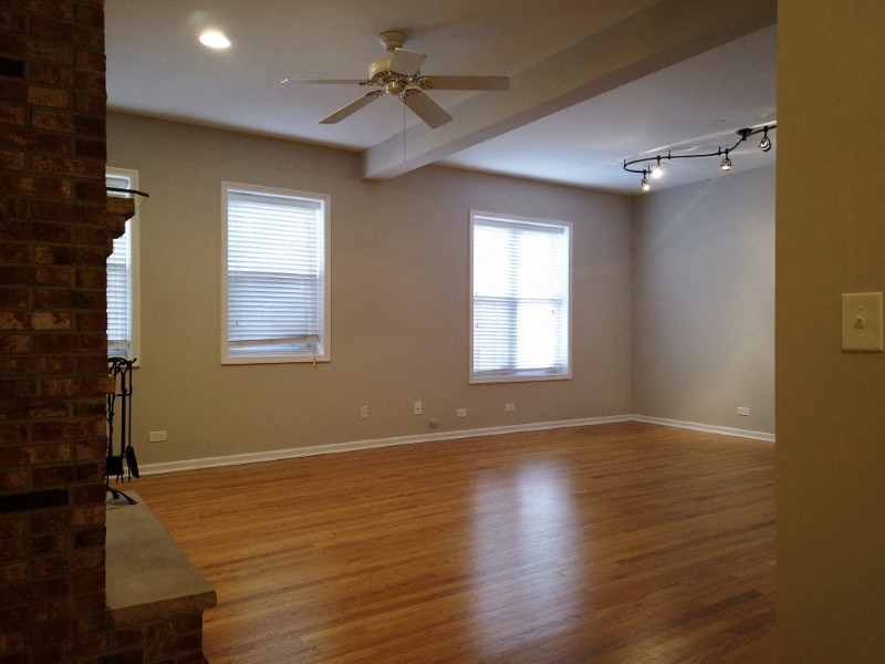 A room with a ceiling fan and two windows.