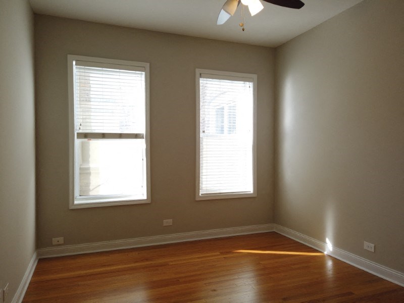 A room with two windows and a ceiling fan.