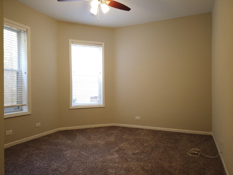 A room with a ceiling fan and a window with blinds.
