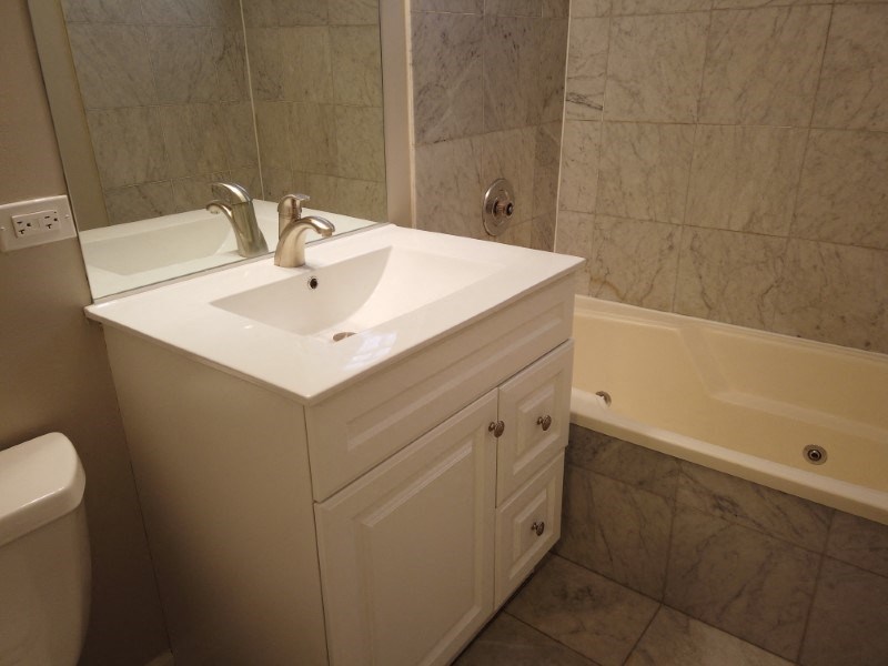 A white sink with a silver faucet is on a white cabinet in a bathroom.