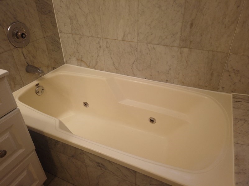 A white bathtub with a shower head above it.