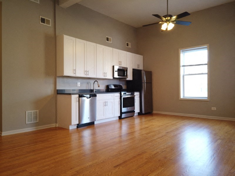 A kitchen with wooden floors and a ceiling fan.