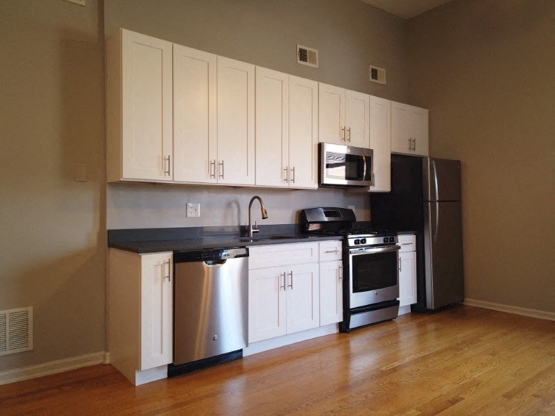 A kitchen with white cabinets and a black countertop.