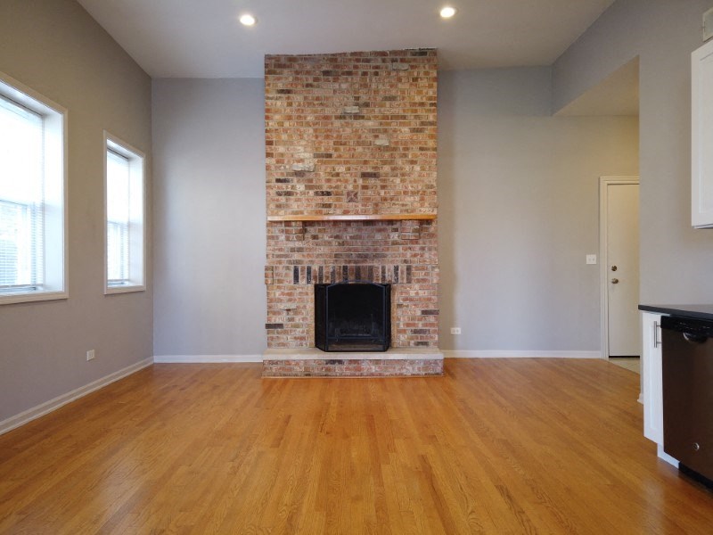 A room with a brick fireplace and wooden floors.