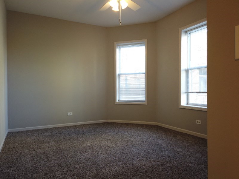 A room with a carpeted floor and two windows.