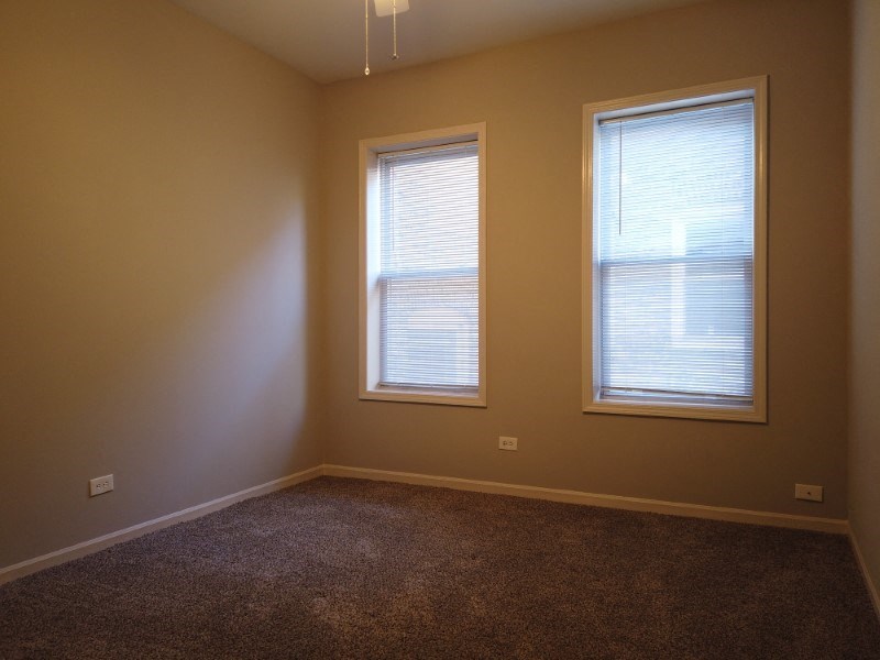 A room with two windows and carpeted floor.