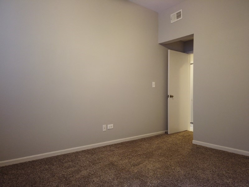 A room with a carpeted floor and a door.