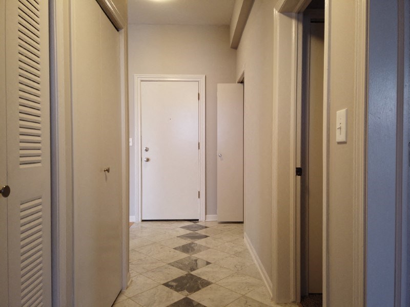 A hallway with white doors and a checkered floor.