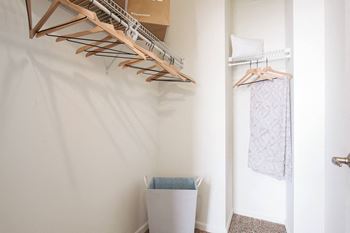 A white wall with a wooden hanger and a white trash can.