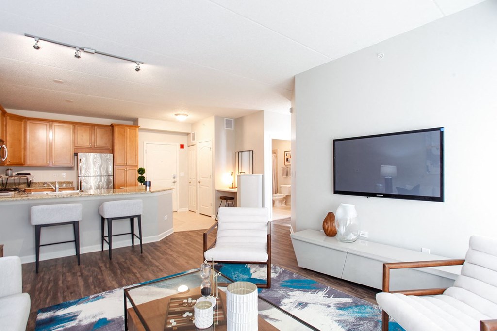 A modern living room with a white couch and a television on the wall.