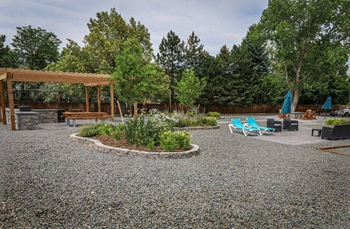 a gravel area with benches and trees in a backyard