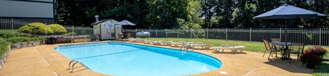 A small pool surrounded by a fence and chairs.