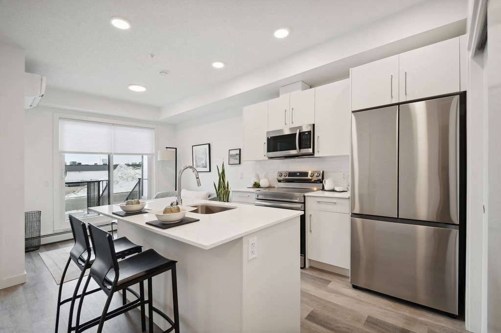 an open kitchen with a large island and stainless steel refrigerator