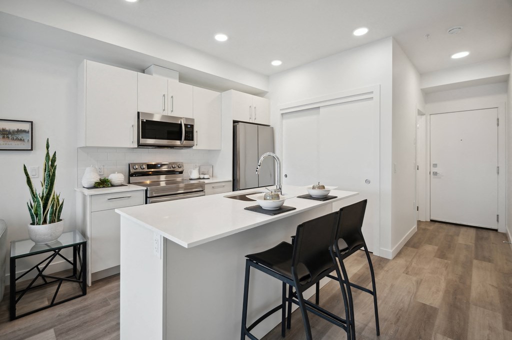 an open kitchen with a large island with two black stools