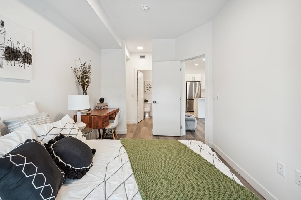 a bedroom with white walls and a bed with pillows and a green blanket